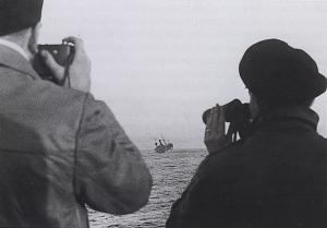 A merchant sinks while an officer photographs the event