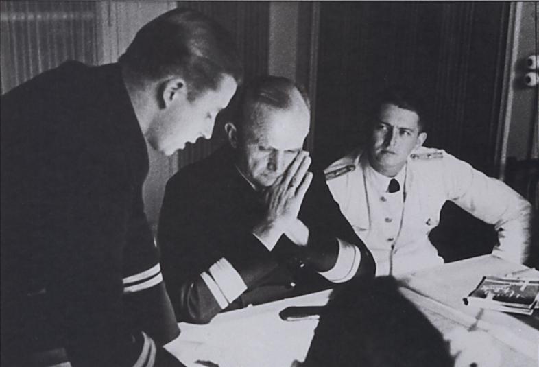 A young U-boat commander on a debriefing with Donitz, while his adjutant (in white...